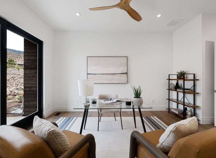 This modern home office features a sleek glass desk with a comfortable chair, perfect for productivity.