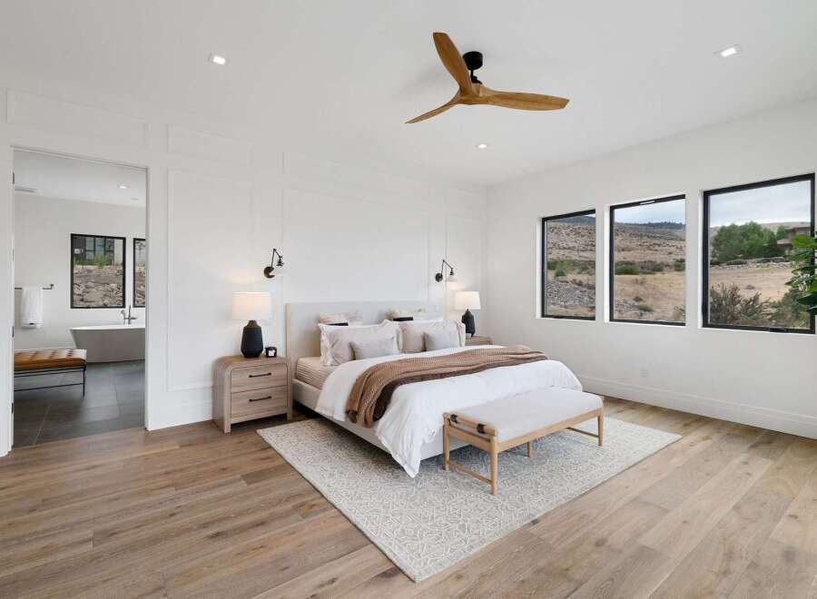 Experience luxury living in this stunning bedroom featuring a king-sized bed adorned with plush linens and a cozy throw.