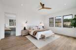 Experience luxury living in this stunning bedroom featuring a king-sized bed adorned with plush linens and a cozy throw.