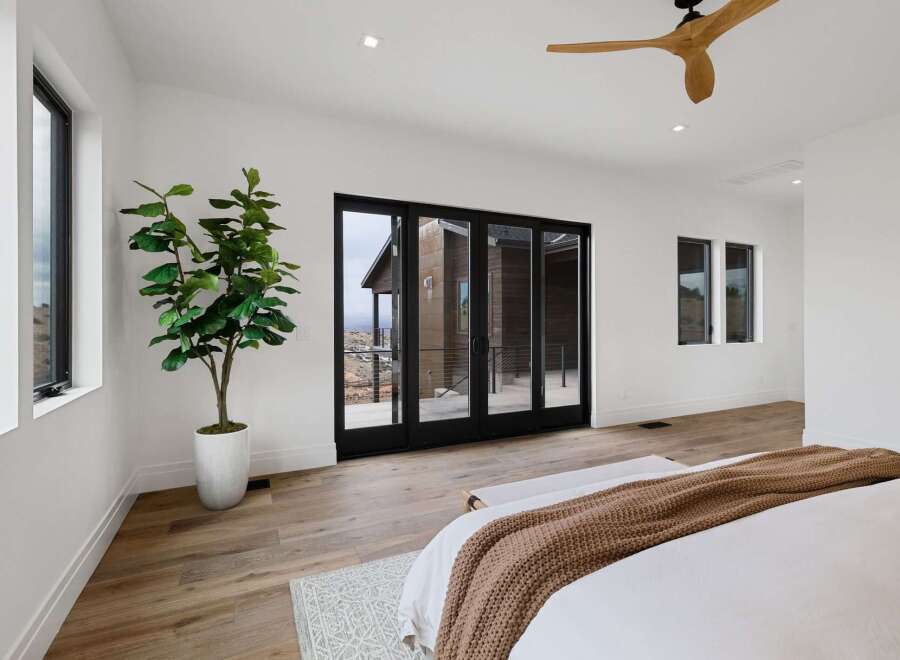 Experience modern luxury in this spacious bedroom featuring expansive glass doors that open to breathtaking views.