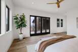 Experience modern luxury in this spacious bedroom featuring expansive glass doors that open to breathtaking views.