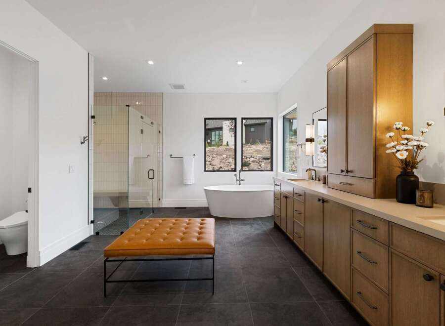 Experience luxury in this stunning modern bathroom featuring a freestanding soaking tub with a view, a spacious glass-enclosed shower, and a double vanity with ample storage.