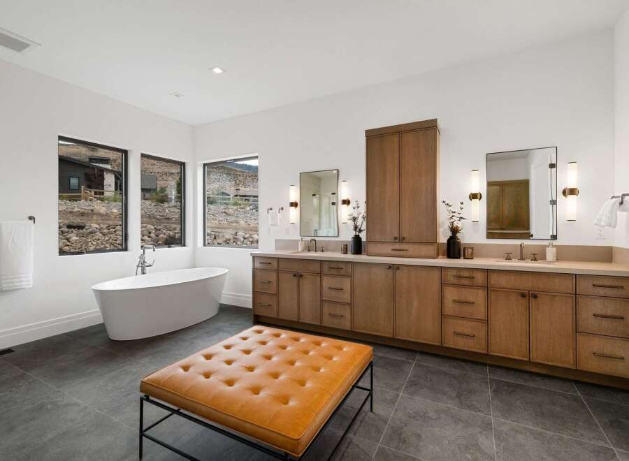 Experience luxury in this stunning modern bathroom featuring a freestanding soaking tub with picturesque views through large windows.