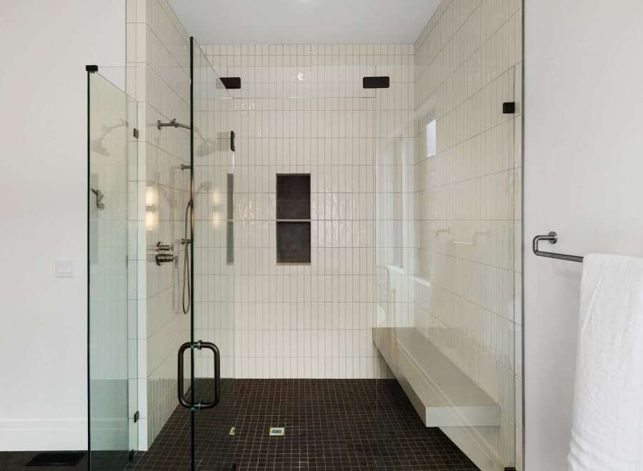 Experience luxury in this modern bathroom featuring a spacious walk-in shower with sleek glass enclosure and vertical white subway tiles.