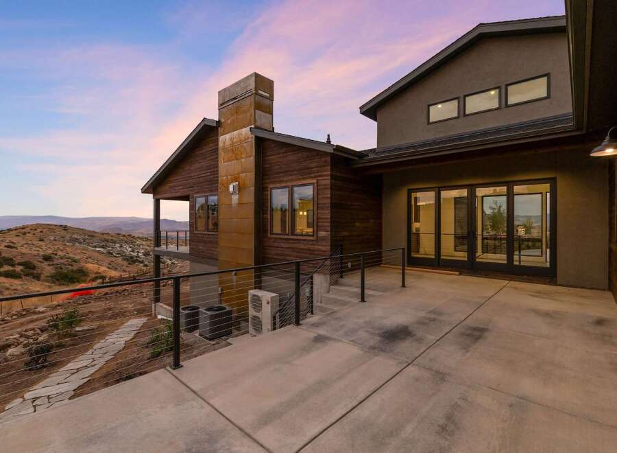 Experience modern luxury in this stunning home, featuring a striking rusted metal chimney and rich wood siding.