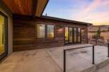 Experience modern living with this stunning home featuring a sleek wooden exterior and expansive concrete patio.
