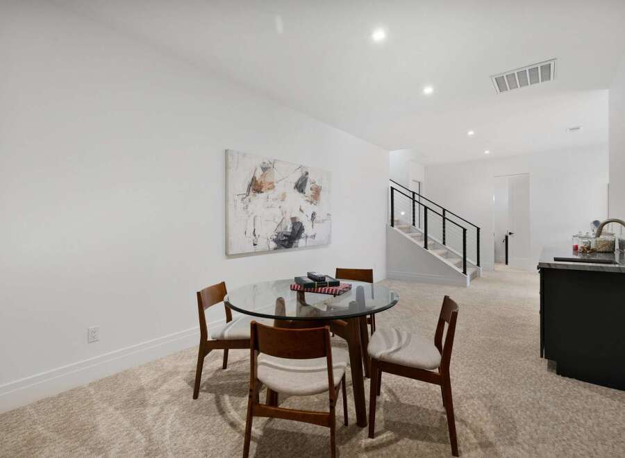 This modern living space features a stylish dining area with a glass-top table and four wooden chairs, perfect for intimate meals.