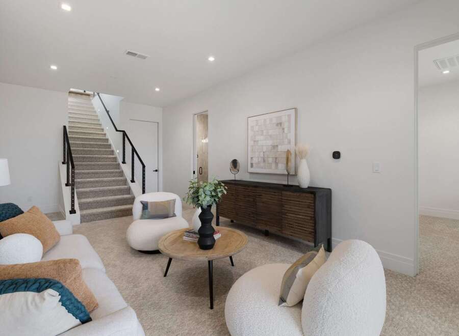 Step into this inviting living space featuring a plush white sofa adorned with accent pillows and a cozy armchair.