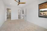 Experience modern luxury in this spacious bedroom featuring a sleek ceiling fan and plush carpeting.