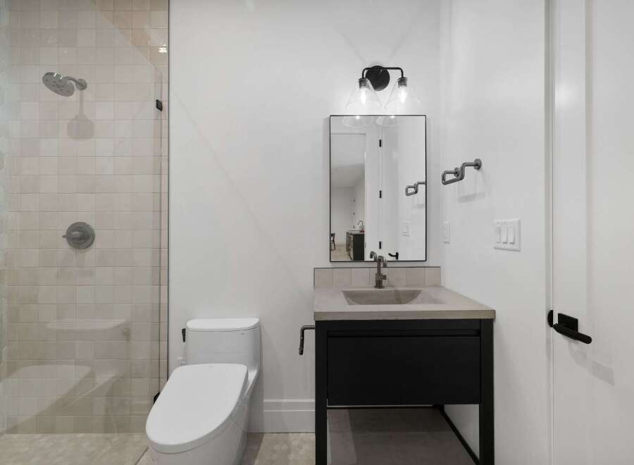 This modern bathroom features a sleek walk-in shower with elegant tilework and a rainfall showerhead.