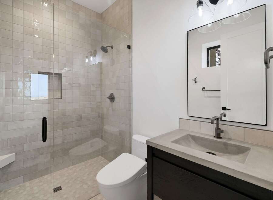 Experience modern luxury in this stunning bathroom, featuring a spacious walk-in shower with elegant tilework and a built-in bench.