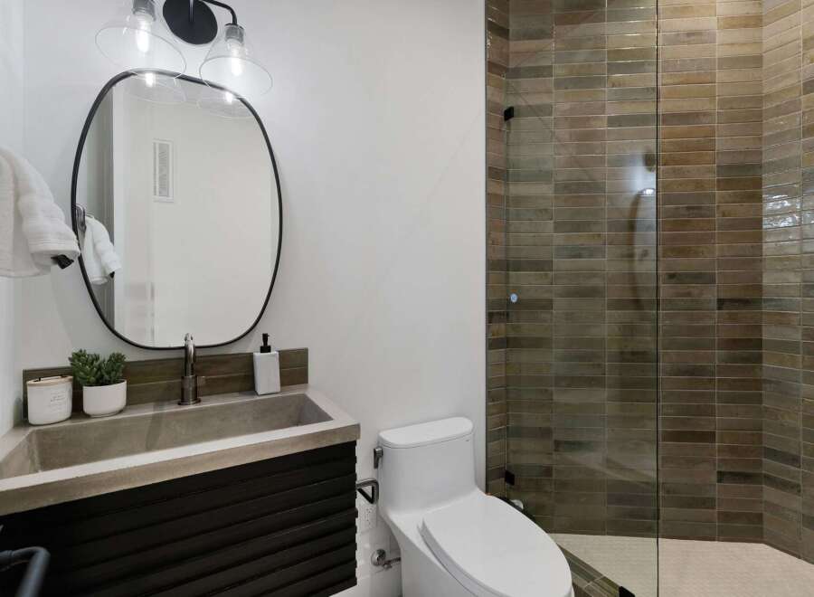 Experience modern luxury in this stunning bathroom, featuring a sleek concrete sink atop a dark wood vanity.