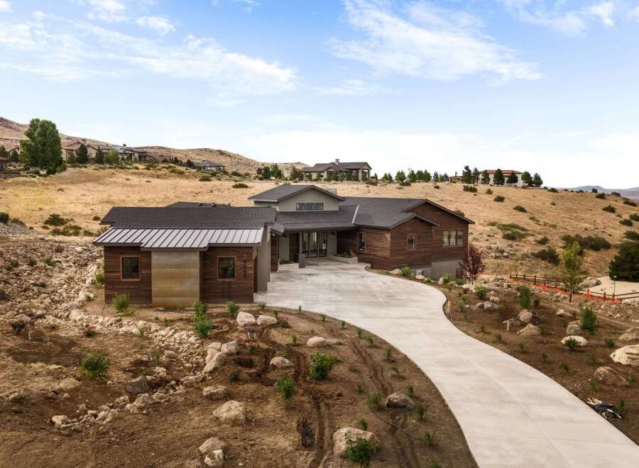 Discover modern luxury living in this stunning hillside estate, featuring a striking contemporary design with rich wood accents and a sleek metal roof.