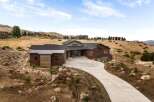 Discover modern luxury living in this stunning hillside estate, featuring a striking contemporary design with rich wood accents and a sleek metal roof.