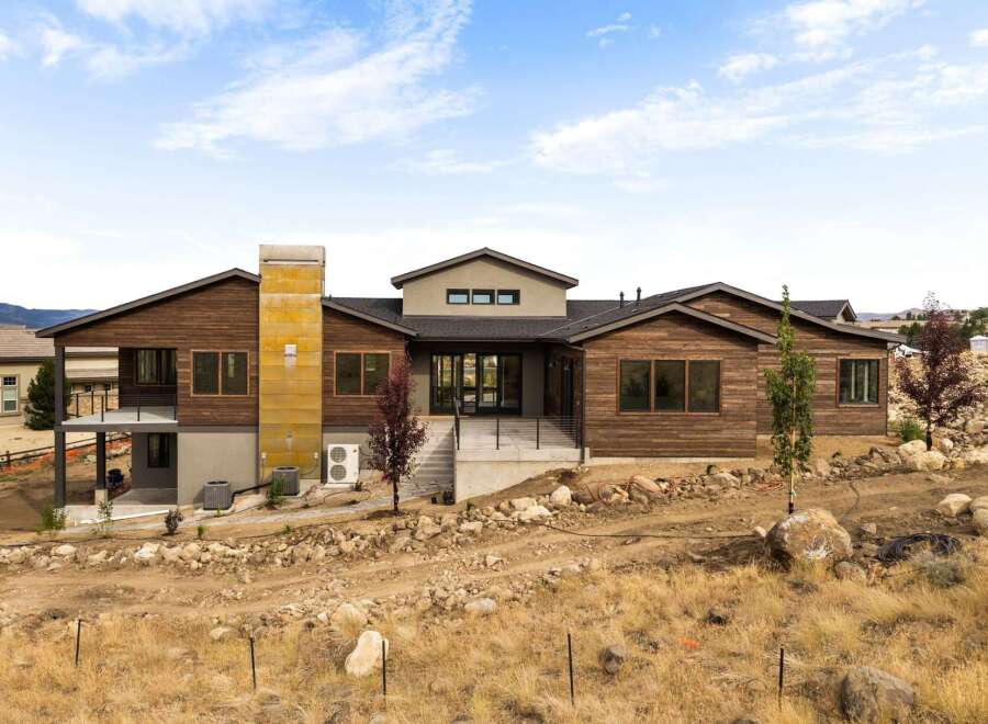 Experience modern living in this stunning custom-built home, featuring a striking exterior with rich wood siding and a unique metal-clad chimney.