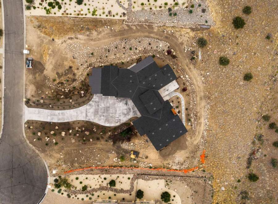Experience modern living in this stunning new construction home, featuring a sleek dark shingle roof and a spacious concrete driveway.