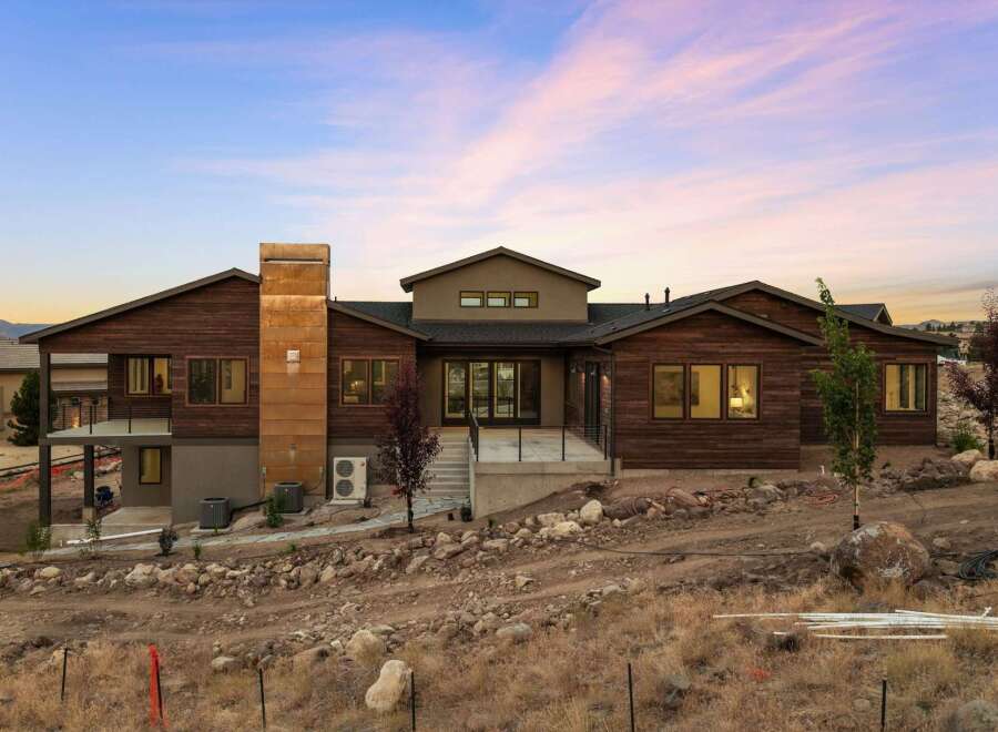 Experience modern luxury in this stunning contemporary home, featuring rich wood siding and a striking metallic chimney.