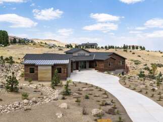 Discover modern luxury in this stunning hillside residence, featuring a striking wood and metal exterior that complements the natural desert landscape.