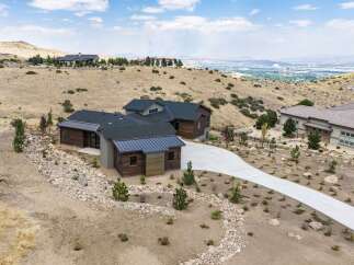 Discover modern luxury in this stunning hillside home, featuring a striking architectural design with rich wood accents and a sleek metal roof.