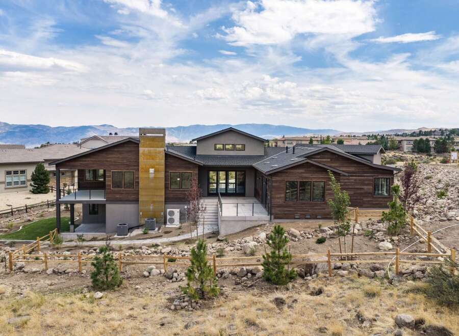 Experience modern luxury in this stunning contemporary home, featuring rich wood siding and a striking metallic chimney.