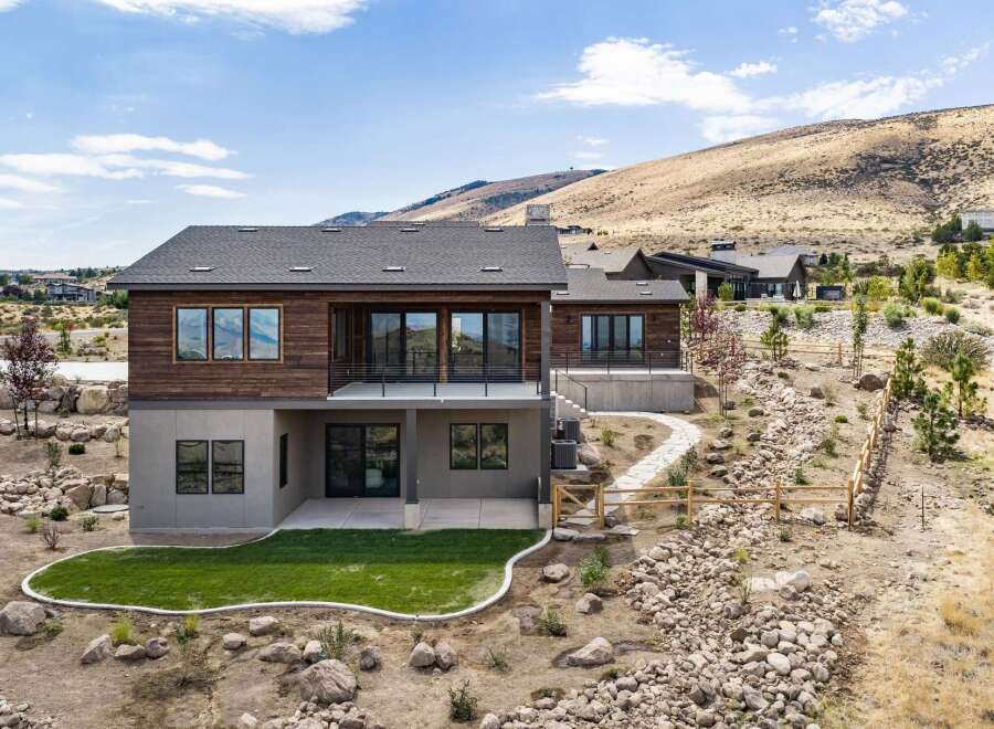 Discover modern luxury in this stunning hillside home, featuring a sleek wood-paneled facade and expansive glass windows that capture breathtaking views.