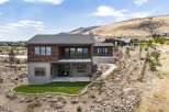 Discover modern luxury in this stunning hillside home, featuring a sleek wood-paneled facade and expansive glass windows that capture breathtaking views.
