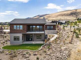 Discover modern luxury in this stunning hillside home, featuring a sleek wood-paneled facade and expansive glass windows that capture breathtaking views.