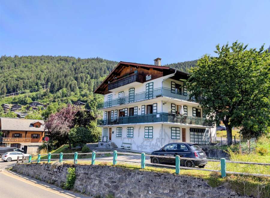 Discover this charming multi-story residence nestled against a lush, forested mountainside, offering breathtaking natural views.