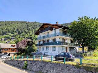 Discover this charming multi-story residence nestled against a lush, forested mountainside, offering breathtaking natural views.