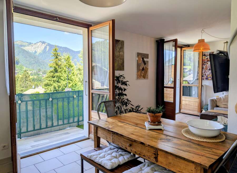 Enjoy breathtaking mountain views from this charming dining area, featuring a rustic wooden table and direct access to a balcony.