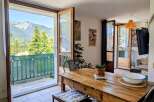 Enjoy breathtaking mountain views from this charming dining area, featuring a rustic wooden table and direct access to a balcony.