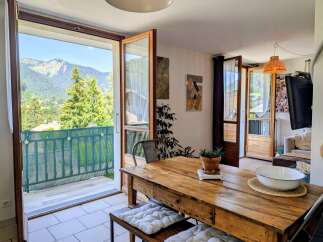 Enjoy breathtaking mountain views from this charming dining area, featuring a rustic wooden table and direct access to a balcony.