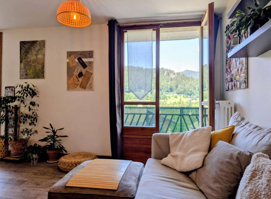 Experience breathtaking mountain views from this charming living room, featuring a comfortable sectional sofa adorned with plush pillows and a cozy throw.