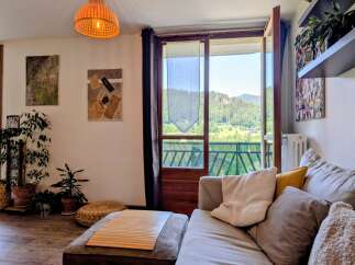 Experience breathtaking mountain views from this charming living room, featuring a comfortable sectional sofa adorned with plush pillows and a cozy throw.