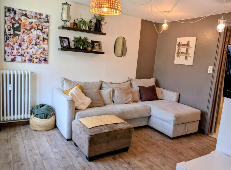This living room features a spacious L-shaped sectional sofa in a neutral tone, complemented by a matching ottoman topped with a bamboo mat.