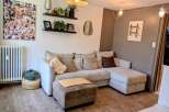 This living room features a spacious L-shaped sectional sofa in a neutral tone, complemented by a matching ottoman topped with a bamboo mat.