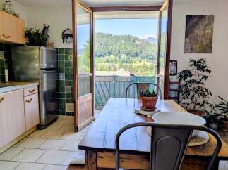 Experience breathtaking mountain views from this charming dining area, featuring a rustic wooden table perfect for family meals.