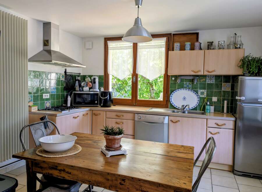 This charming kitchen features a rustic wooden dining table, perfect for family meals.