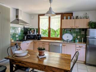 This charming kitchen features a rustic wooden dining table, perfect for family meals.