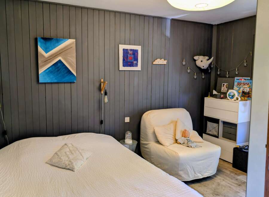 This cozy bedroom features a comfortable bed with a textured white duvet and a decorative pillow.