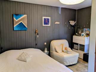 This cozy bedroom features a comfortable bed with a textured white duvet and a decorative pillow.