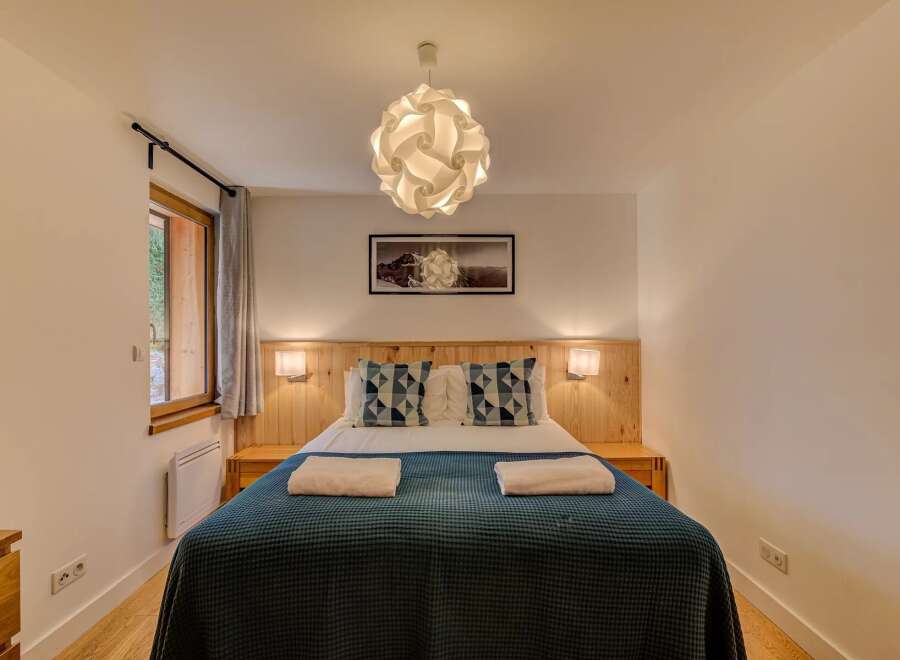 Experience cozy comfort in this charming bedroom, featuring a plush bed adorned with decorative pillows and soft throws.