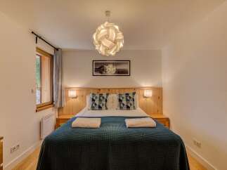 Experience cozy comfort in this charming bedroom, featuring a plush bed adorned with decorative pillows and soft throws.
