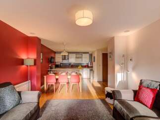 Experience modern living in this open-plan apartment featuring a vibrant red accent wall and a fully equipped kitchen with sleek cabinetry.
