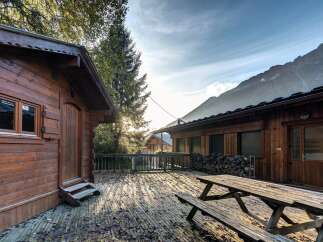 Experience the charm of mountain living with this rustic wooden cabin, featuring a spacious deck perfect for enjoying the crisp alpine air.