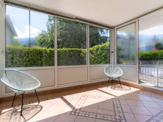 Enjoy your morning coffee or evening relaxation in this sun-drenched enclosed patio, featuring two stylish white Acapulco chairs.