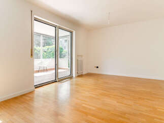 Step into this bright and airy living space featuring gleaming hardwood floors and expansive glass doors that open to a charming balcony.