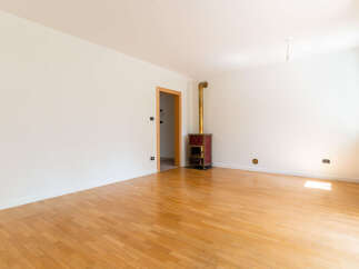 Discover this spacious room featuring a beautiful hardwood floor and a charming red stove with a golden chimney.
