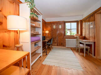 This charming room features warm, wood-paneled walls and a cozy atmosphere, perfect for a home office or study nook.