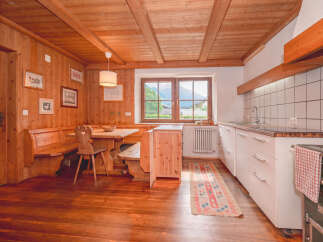 Experience rustic charm in this cozy kitchen and dining area, featuring warm wooden paneling and a traditional built-in banquette.